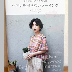 Può includere: Un libro con copertina flessibile intitolato ゼロウェイストの大人服 ハギレを出さないソーイング che mostra una persona che indossa un top a quadri multicolore a maniche corte e pantaloni chiari. La copertina include il testo Participating Designers, Danielle Elsener, Liz Haywood e Birgitta Helmersson.