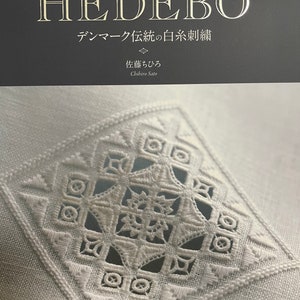 Può includere: Un libro intitolato "HEDEBO" con il sottotitolo "Tradizione danese del ricamo con filo bianco" in giapponese. La copertina del libro presenta un ricamo bianco su uno sfondo di tessuto bianco.