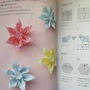 May include: Instructions for folding a paper origami flower in the shape of a clematis. The instructions are written in Japanese. The origami flower is shown in three different colors: red and white stripes, yellow and white stripes, and blue and white stripes. The finished origami flower is 9.5 inches by 9.5 inches.