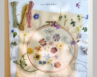 May include: A craft book titled 草花刺繍 featuring a round wooden embroidery hoop with floral stitching on cream fabric. The cover displays colorful embroidery floss, pressed flowers, and Japanese text, showcasing botanical needlework techniques.