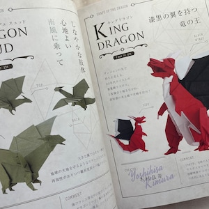 May include: A book open to two pages showing origami dragon designs. The left page shows a green origami dragon with the title "Dragon Du Sud" and the right page shows a red and black origami dragon with the title "King Dragon".