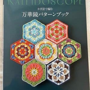 May include: A book titled "Kaleidoscope" with the Japanese text "かぎ針で編む 万華鏡パターンブック" and the text "Pomadour's" on the cover. The book features a colorful crocheted design of hexagonal shapes.