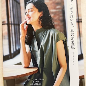 May include: A book cover with a woman wearing a green sleeveless shirt and a silver bracelet. The book title is "Silhouettes that are beautiful, my staple clothes" in Japanese. The book cover also includes the text "Heart Warming Life Series" and "S-M-L-2L-3L-4L Sizes of actual large paper included".
