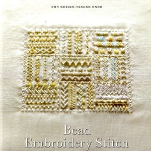 Puede incluir: Portada de libro con un muestrario de bordado de cuentas detallado. El diseño es un cuadrado compuesto por varios patrones de puntadas en cuentas doradas, amarillas y celeste sobre un fondo crema. Texto en japonés en la parte superior, título "Bead Embroidery Stitch Samplers 130" en la parte inferior.