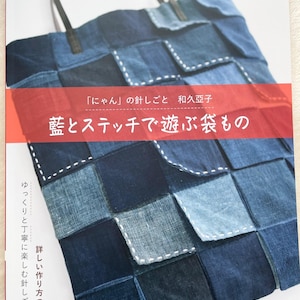 May include: A patchwork denim tote bag with a variety of blue squares. The bag has leather handles and a red banner with Japanese text. The book cover also includes Japanese text and the word "Pomadour's".