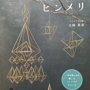 May include: A book cover with a gold geometric mobile made of straw hanging from the ceiling. The book title is "四季を彩る美しいヒンメリ" which translates to "Beautiful Hinmeri that Colors the Four Seasons". The book cover is gray with a branch of a tree in the background.