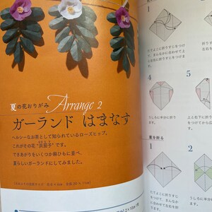 May include: A page from a craft book showing how to make a paper rose garland. The instructions are written in Japanese. The image shows a close-up of the folded paper rose and the steps to create it. The text on the page says "Summer's scent, Arrange 2, Garland, Rosehip".