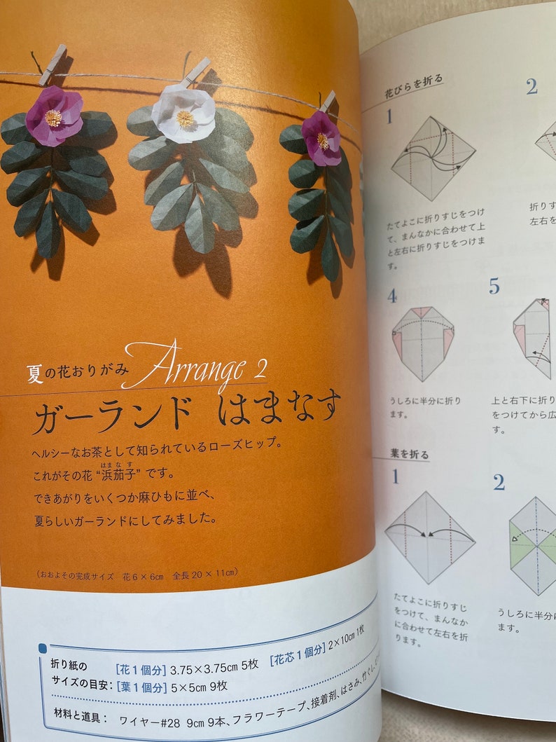 May include: A page from a craft book showing how to make a paper rose garland. The instructions are written in Japanese. The image shows a close-up of the folded paper rose and the steps to create it. The text on the page says "Summer's scent, Arrange 2, Garland, Rosehip".