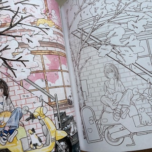 May include: An open colouring book featuring two pages with identical line art illustrations. The left page is partially coloured with a yellow scooter, a person, and cats under a tree. The right page shows the same scene in black and white outlines.
