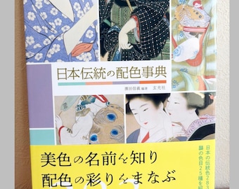 May include: A book titled 日本伝統の配色事典 featuring a collage of traditional Japanese illustrations on the cover. The cover displays figures in patterned kimonos, a bright yellow lower section with the text 283色 25種, and white Japanese characters.