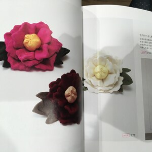 May include: Three fabric flowers, two pink and one white, with yellow centers and green leaves. The flowers are arranged on a white background with text in Japanese.