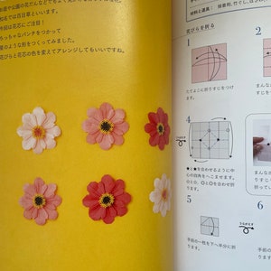 May include: A step-by-step guide on how to fold a paper zinnia flower. The instructions are written in Japanese and include diagrams showing the folding process. The finished flower is pink with a brown center.