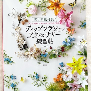 May include: A book cover with a white background and a colorful floral design. The book title is "Dip Flower Accessories Practice Book" in Japanese. The book cover features a variety of flowers, including lilies, roses, and forget-me-nots, as well as butterflies. The book is by m.n.c. and published by Kodansha.
