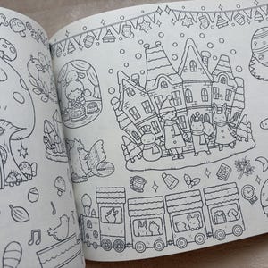 May include: Open coloring book pages with detailed black and white illustrations. One page depicts a fairy village with houses, characters, and a train. The other page shows a large mushroom house and other fantasy elements. The drawings are outlined in black.