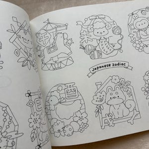 May include: Open book featuring black and white illustrations of Japanese zodiac animals. The drawings include a tiger, horse, sheep, monkey, dog, and pig. The text "Japanese zodiac" is written on a banner.
