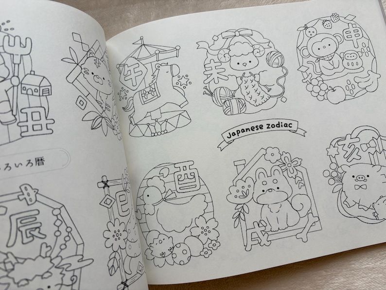 May include: Open book featuring black and white illustrations of Japanese zodiac animals. The drawings include a tiger, horse, sheep, monkey, dog, and pig. The text "Japanese zodiac" is written on a banner.