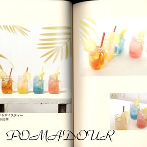 May include: Four mason jars filled with colorful liquids and topped with lemon slices and straws. The jars are arranged on a wooden table with a leafy background. The text "レモネード & アイスティー  檸檬水 & 氷紅茶" is written below the jars.
