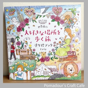 May include: A square coloring book with a colorful illustration. The cover features a woman in a green dress, suitcases, and various drawings of landmarks and animals. Japanese text is visible. The book is titled "Eriy" and is from "Pomadour's Craft Cafe."