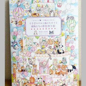 May include: A colorful coloring book cover featuring a whimsical illustration of various animals, including cats, bears, and pandas, arranged around a multi-tiered cake. The book's title is in Japanese, with the author's name below.