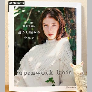 May include: A book cover with a woman in a white openwork knit sweater. The book title is "openwork knit" with Japanese text above. The "applemints" logo is in the upper left corner. A small llama figurine is on the right.