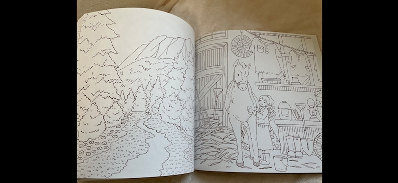 Puede incluir: Un libro para colorear abierto en dos p&aacute;ginas. Una p&aacute;gina presenta un paisaje detallado de un bosque y monta&ntilde;as. La otra p&aacute;gina muestra a una ni&ntilde;a con un caballo dentro de un granero, con varias herramientas y ropa.