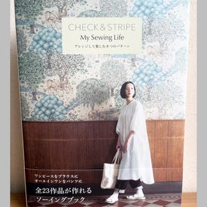 以下が含まれることがあります： 「CHECK & STRIPE My Sewing Life」というタイトルのソーイングブック。表紙には森の風景と白いドレスを着た女性が描かれています。この本は23のソーイングプロジェクトを掲載しています。