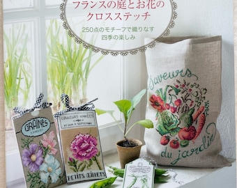 Op de afbeelding: Boekomslag met een kruissteekontwerp van een tuin met bloemen, groenten en een aardbei. De titel van het boek is "Franse tuin en bloemen kruissteek" en de ondertitel is "250 motieven om de vier seizoenen te weven".