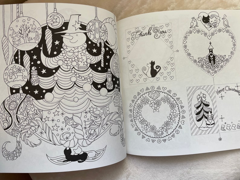 May include: A black and white coloring book page featuring a snowman in a hat and scarf, surrounded by Christmas ornaments and a Christmas tree. The page also includes several other designs, including a heart-shaped wreath, a Christmas card with a tree, and a thank you card with a cat.