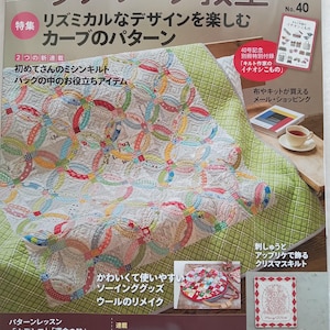 May include: A magazine cover featuring a colorful patchwork quilt with a circular design. The cover includes Japanese text and the title "Patchwork Classroom." Additional images showcase sewing projects and a cup of tea.