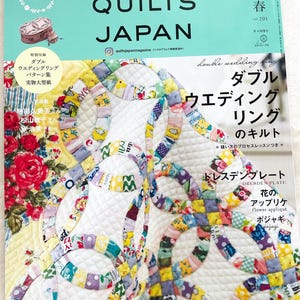 May include: A magazine cover showcasing a vibrant quilt design with the title "Quilts Japan" and the text "Double Wedding Ring" in a circle. The magazine is a guide to quilting, focusing on the double wedding ring pattern.