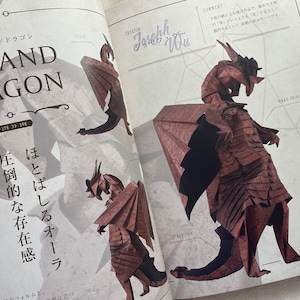 May include: A brown origami dragon with a scaly tail and hard skin. The dragon is standing on a white surface with a grid pattern. The text "Grand Dragon" is written in large letters at the top of the page. The text "Creator Joseph Wu" is written in the upper right corner of the page.