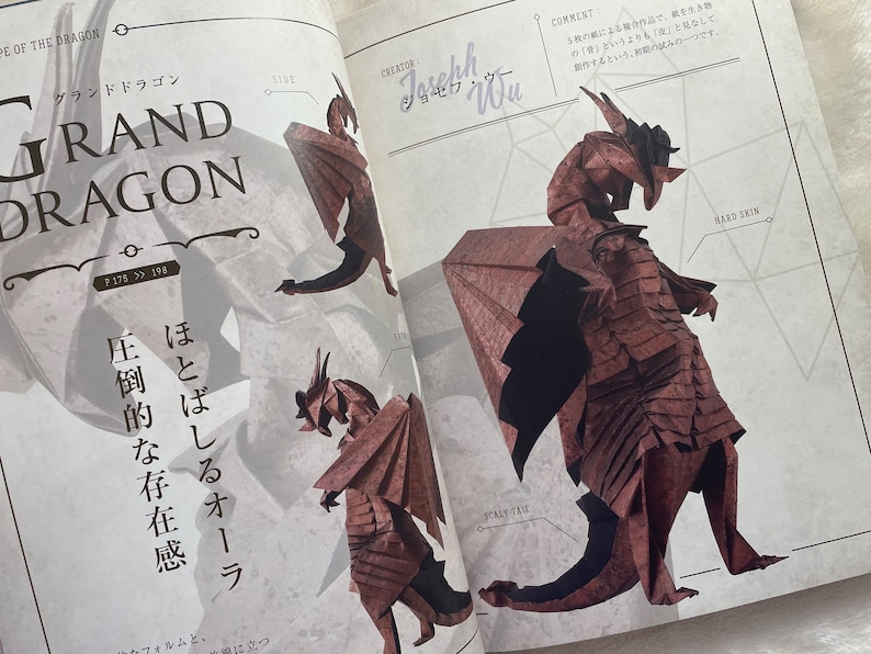 May include: A brown origami dragon with a scaly tail and hard skin. The dragon is standing on a white surface with a grid pattern. The text "Grand Dragon" is written in large letters at the top of the page. The text "Creator Joseph Wu" is written in the upper right corner of the page.