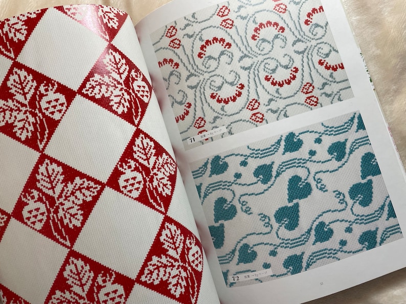 May include: A book with three different cross-stitch patterns. The first pattern is a red and white checkered pattern with a leaf and berry design. The second pattern is a light blue and white pattern with a floral design. The third pattern is a teal and white pattern with a leaf design.