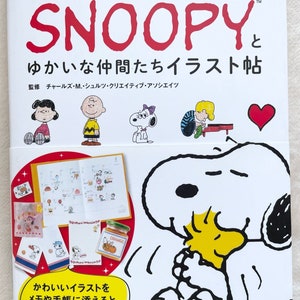 May include: A book cover featuring Snoopy and his friends from the Peanuts comic strip. The cover is red, white, and black with the title "Snoopy ゆかいな仲間たちイラスト帖" in Japanese. The book is a guide to drawing Snoopy and his friends.