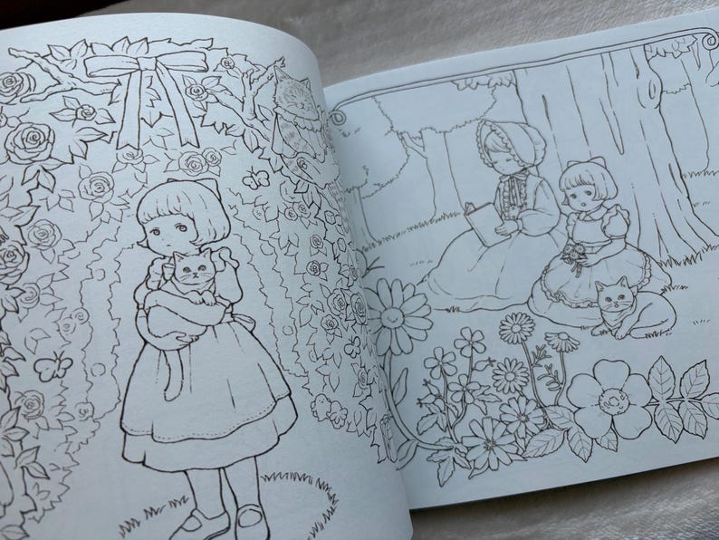 May include: Open book with black and white illustrations. One page shows a girl holding a cat in a garden of roses. The other page depicts two girls and a cat under a tree. Coloring book pages.