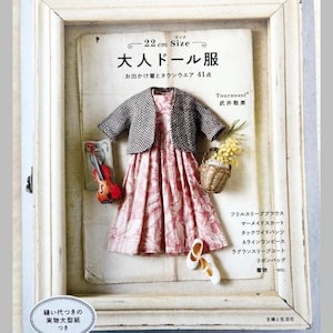 Puede incluir: Imagen enmarcada de un vestido de muñeca y accesorios. El vestido es rosa con un estampado floral blanco, combinado con una chaqueta gris y negra. Incluye un violín en miniatura, una cesta de flores y bailarinas. Texto: "22 cm Size" y "Pomadour's".