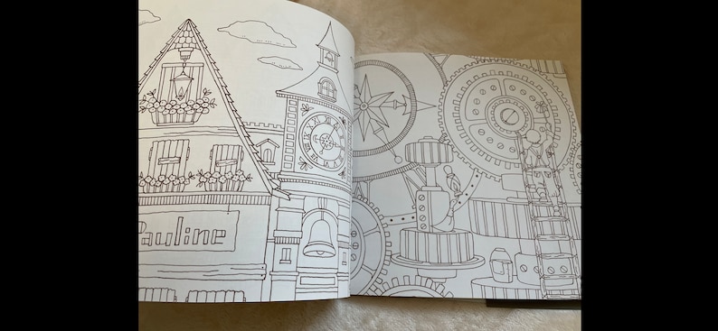 Puede incluir: Libro para colorear abierto con ilustraciones detalladas en l&iacute;nea. Una p&aacute;gina muestra un edificio con una torre de reloj, el nombre "Pauline" en un letrero y detalles florales. La otra p&aacute;gina representa engranajes, una rosa de los vientos y elementos mec&aacute;nicos.