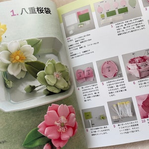 May include: A step-by-step guide on how to make a felt cherry blossom flower. The instructions are written in Japanese and include images of each step. The finished flower is pink and has a delicate, layered look.