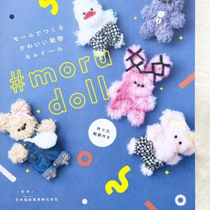 Op de afbeelding: Een boekomslag met een blauwe achtergrond en kleurrijke geometrische vormen. De titel van het boek is "#moru doll" en de ondertitel is "モールでつくる かわいい動物 モルドール" in het Japans. De omslag toont vijf pluche dieren: een roze konijn, een paarse beer, een witte eend, een roze beer met een strik en een beige beer met een overall.