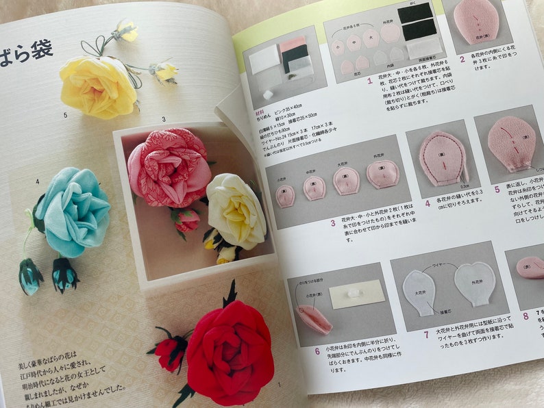 May include: A book with instructions on how to make fabric roses. The book shows different colored roses, including pink, blue, white, and red. The book also shows the steps involved in making the roses.