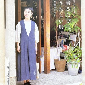 以下が含まれることがあります： 青いジャンプスーツと白いシャツを着た女性が表紙の書籍。書籍のタイトルは「着るたびに嬉しい服」と日本語で書かれている。書籍は「Heart Warming Life」シリーズの一部である。