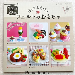 Op de afbeelding: Een knutselboek met vilten voedsel speelgoed, waaronder ijs, een lunchbox, cupcakes, een hamburger lunch, wafels en een omelet rijst lunch. De omslag heeft Japanse tekst en illustraties van de vilten voedingsmiddelen. Het boek heet "Speelgoed maken met vilt".