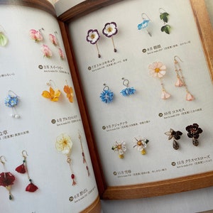 May include: A collection of 12 pairs of handmade flower earrings. Each pair features a different flower, including a white cosmos, a red poppy, a blue forget-me-not, and a yellow daffodil. The earrings are made with delicate details and are perfect for adding a touch of nature to any outfit.