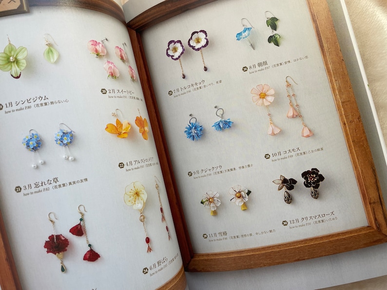 May include: A collection of 12 pairs of handmade flower earrings. Each pair features a different flower, including a white cosmos, a red poppy, a blue forget-me-not, and a yellow daffodil. The earrings are made with delicate details and are perfect for adding a touch of nature to any outfit.