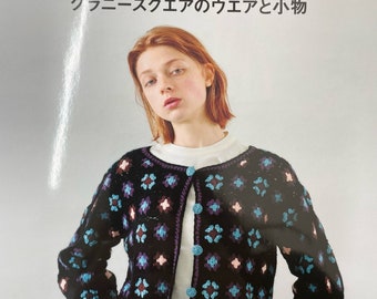 Pode incluir: Uma capa de livro com uma mulher vestindo um casaco de crochê preto com um padrão de granny square em tons de azul, roxo e rosa. O título do livro é "GRANNY square" em letras grandes e em negrito. O texto abaixo do título diz "かぎ針で編む グラニースクエアのウエアと小物" e a parte inferior da capa diz "Pomadour's Craft Cafe".
