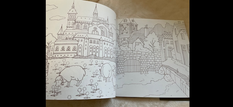 Puede incluir: Una p&aacute;gina doble de un libro para colorear en blanco y negro con ilustraciones detalladas de un castillo, edificios, ovejas y un paisaje urbano. Los dibujos son intrincados y adecuados para colorear.