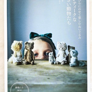 May include: A book cover with a girl peeking over a table with a row of small stuffed animals. The book title is "Antique-like Small Animals" and the text "14 Recipes" is in a circle. The book is titled "Pomadour's Craft Cafe."