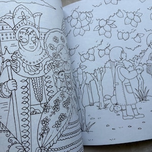 May include: Black and white line art coloring book pages. One page features a costumed figure with a star-topped staff. The other page shows children gathering fruit from trees. The book is open, revealing the detailed illustrations.