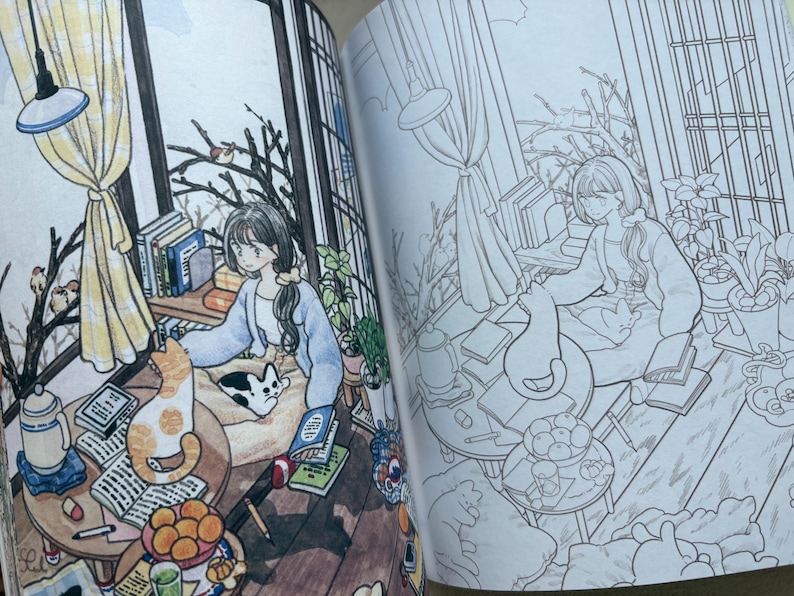 May include: An open colouring book featuring two side-by-side illustrations of a cosy room. One page is fully coloured with warm tones, showing a person sitting with a cat, books, and fruit. The other page is a black and white line art outline.