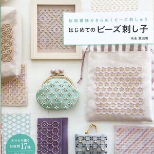 Può includere: Una copertina di libro con uno sfondo rosa chiaro e il titolo "はじめてのビーズ刺し子" (Hajimete no Beads Sashiko) in testo nero. La copertina del libro presenta vari oggetti artigianali perlati, tra cui una piccola borsa a mano, un portafoglio per monete e un pezzo di stoffa incorniciato con un motivo geometrico. La copertina del libro include anche il testo "キラキラ輝く 伝統柄17種" (Kirakira Kagayaku Dentougara 17 Shu) in un cerchio.